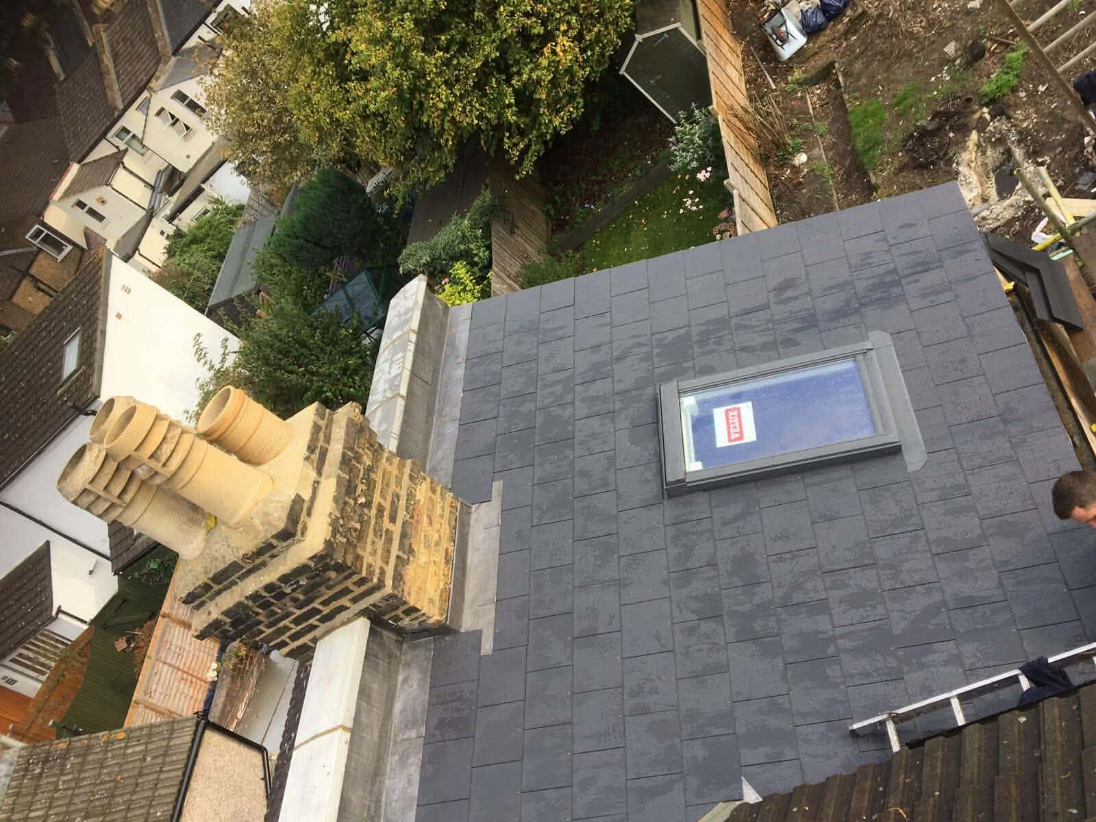 Completed residential roof replacement with clean slate tile finish and aligned ridge details