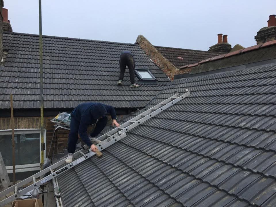 Workers carrying out roofing works in progress with scaffolding and site controls
